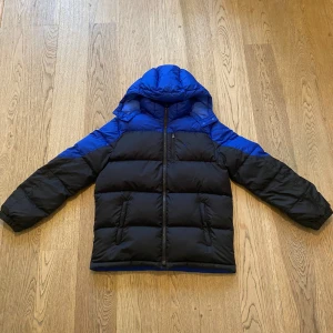  Ralph Lauren dunjacka  - Säljer en snygg och varm pufferjacka från Ralph Lauren i blått och svart. Xl barn men passar som man s. Luvan är avtagbar. Jätte fint skick 