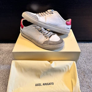 Vita sneakers från Axel Arigato - Säljer nu mina vita axel arigato skor. Skorna är i helt okej skick, se bilder. Men de har fortfarande mycket kvar att ge! Orginalbox och dustbag medföljer. Hör av dig vid minsta funderingar eller frågor😊