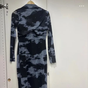 Svart och grå mönstrad klänning - Snygg långärmad klänning i svart och grått med ett unikt mönster. Perfekt för höst och vinter, den är både stilren och bekväm. Klänningen har en tight passform som framhäver figuren. Perfekt för en kväll ute eller en speciell tillställning. (Vet ej ifall det är riktig)