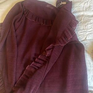 Vinröd klänning med volangdetaljer - Säljer en superfin vinröd topp från Pieces. Den har volangdetaljer längs halsen och ärmarna, vilket ger en romantisk touch. Perfekt för höst och vinter, och kan stylas både upp och ner beroende på tillfälle. Så fin❤️🍓