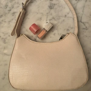 Vit handväska  - Fin handväska ifrån Gina tricot gjord utav polyester. Väskan är i bra skick och har bara används några fåtal gånger. Mycket fin till både vardags och till lite finare event.