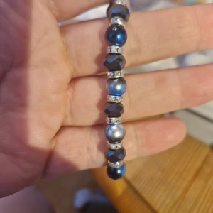 Blått och svart pärlarmband - Snyggt armband med blå och marinblå pärlor, perfekt för att ge lite extra stil till din outfit. Pärlorna är glansiga och varvas med små glittriga detaljer som ger en lyxig känsla. Passar både till vardags och festliga tillfällen. Stretchigt för enkel passform.