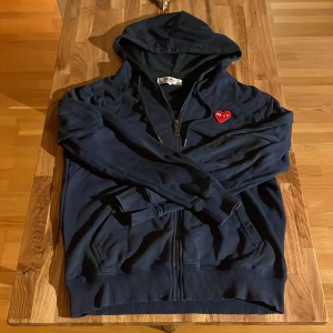 Mörkblå cdg play hoodie  - Säljer min cdg play hoodie eftersom att den är förliten men den är i hyfsat bra skick den har inga hål och den passar bra till det mesta                         Pris går att diskutera 