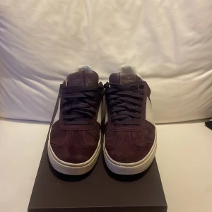 Lilla Valentino flycrew sneakers med vita detaljer - Säljer ett par Lilla Valentino flycrew sneakers med vita detaljer och klassisk snörning. Skorna har en vit panel på sidan och vit häl, samt nitar längs sulans bakkant. Perfekta för dig som vill ha något unikt och stilrent. plus allt og 