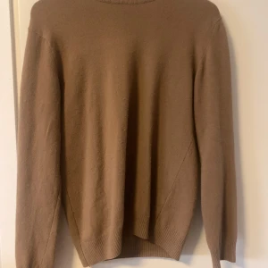 Beige kashmirtröja från Oscar Jacobson - Säljer en klassisk beige kashmirtröja från Oscar Jacobson. Tröjan har rund halsringning och långa ärmar, perfekt för kyliga dagar. Tillverkad i mjuk kashmir och har en stilren, tidlös design. 