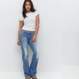 Blå bootcut jeans med slitningar - Säljer ett par blå bootcut jeans med slitna detaljer från tian tricot. framtill och bakfickor med broderade detaljer. Jeansen har normal passform och klassisk femficksdesign. Perfekta för en avslappnad och trendig look. (Ny pris 429) 