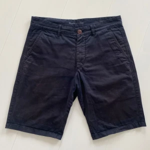 Mörkblå shorts från Marc O'Polo - Stilrena mörkblå shorts från Marc O'Polo med normal passform. Klassisk design med snedställda fickor fram och två fickor med lock bak. Perfekta för sommaren och tillverkade i mjuk bomull.