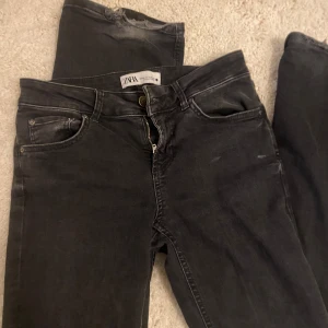 Svarta Low waist jeans från Zara - Svarta jeans från Zara med klassisk femficksdesign och dragkedja. Jeansen är slitna längst ner som syns på bilderna💕