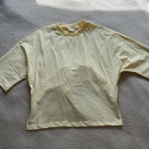 Ljusgul croppad topp med knyt från Nelly - Säljer en ljusgul croppad topp från Nelly med rund halsringning och korta ärmar. Aldrig använd ändast testad