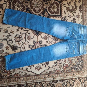 Blå raka jeans från Levi's - Klassiska blå jeans från Levi's med raka ben och femficksdesign. Jeansen har tydliga sömmar på bakfickorna och en ljus tvätt på låren. Perfekta för en avslappnad stil.
