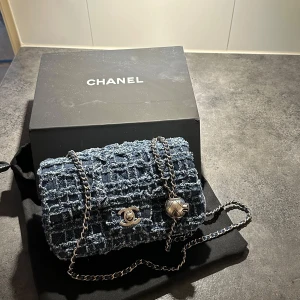 Denim bag - Säljer en blå axelväska i tweed med silverfärgade metalldetaljer och kedjerem. Väskan har klassiskt CC-spänne och quiltad struktur.