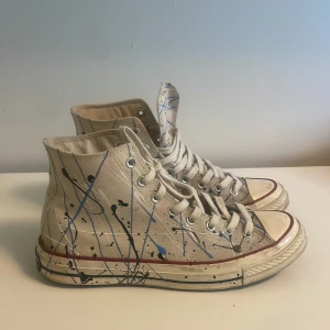 Converse All Star sneakers med färgstänk - Säljer ett par ”cream” vita Converse All Star high-top sneakers med färgstänksmönster i blått och svart. Storlek 44,5 (29cm). Ingen OG box och vissa defekter (skriv för fler bilder).