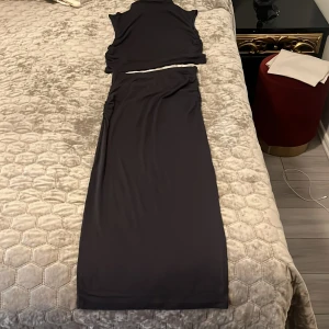 Mörk blå kjol top sett  - Säljer den virala settet med ärmlös topp och lång kjol. Setter har rynkade detaljer i sidorna och är tillverkad i ett mjukt, stretchigt material. Perfekt för dig som vill ha en stilren och modern look. Går att köpa separat 