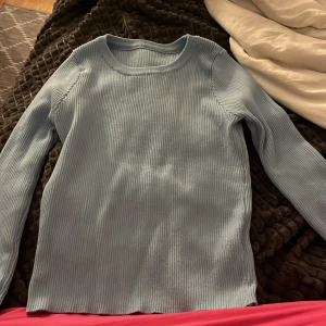 Ljusblå ribbad långärmad tröja - Säljer en ljusblå långärmad tröja med ribbad struktur. Tröjan har rund halsringning och är i ett mjukt, stretchigt material som sitter bekvämt på kroppen. Perfekt för lager-på-lager eller som den är.Storelk M men sitter ändå bra till folk med storlek S