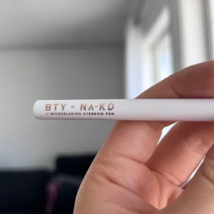 BTY by NA-KD Microblading Eyebrow Pen - Säljer en BTY by NA-KD microblading eyebrow pen. Pennan har en tunn, precisionsspets för att skapa naturliga brynstrån. Innehåller 0,6 ml och är vegansk. Perfekt för att fylla i och forma ögonbrynen. Önskar du veta något mer? Tveka inte att höra av dig!