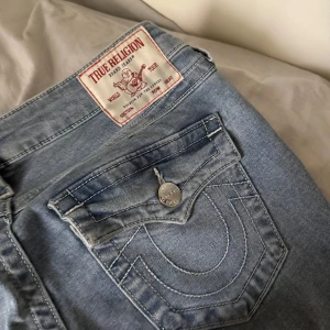 True Religion Joey Low Rise Flare Jeans - Säljer ett par ljusblåa True Religion jeans, modell Joey med låg midja och utsvängda ben. Pågrund av att storleken inte passar mig, har använt dom 3 gånger ungefär. Det är storlek 26💗