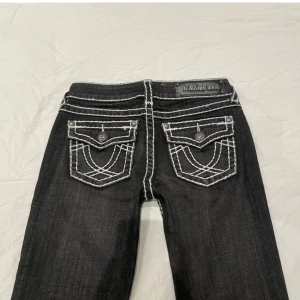 Svarta bootcut jeans med vit kontrastsöm från LA Idol USA - Snygga tru religion-liknande jeans. Låg midja och slim/bootcut! Köpte den för 700kr säljer för 550kr. Midja ca 78cm o innerben ca 84cm. Jag är 160cm och dem är lite långa på mig så skulle nog säga att dem skulle passar perfekt på någon som är 165cm lång. Dem är lite slitna längst ner 