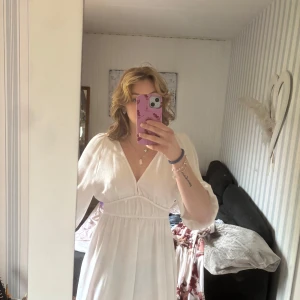 Vit  med öppen rygg  - Säljer en vit klänning med v-ringning och långa ärmar. Klänningen har en öppen rygg med resår i midjan för en smickrande passform. Perfekt för sommarens alla tillfällen!