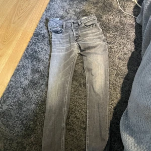 Grå slim jeans från Diesel - Säljer ett par grå skim jeans från Diesel med snygga detaljer och klassiska fem fickor. Jeansen har låg midja och raka sömmar, tillverkade i mjukt denimtyg med stretch för extra komfort. Perfekta för dig som gillar en smal passform och cool tvätt.