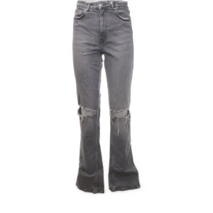 Grå bootcut jeans med slitna knän - Säljer ett par gråa bootcut jeans med snygga slitningar över knäna och slits i slutet av byxorna . Hög midja och klassisk femficksmodell. Perfekta för dig som gillar en avslappnad men trendig look.