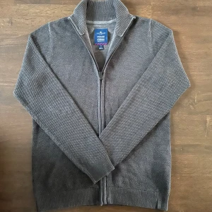 Tom Tailor tröja  - Säljer en grå stickad kofta från Tom Tailor i nytt skick (endast testad). Perfekta tröjan inför sommaren med full zip och en skön grå färg. Pris kan diskuteras vid snabb affär, skriv privat vid minsta fundering👍🏻🙌🏻
