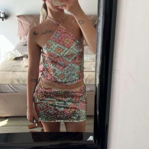 Paljettkjol i pastell med mönster - Superfin kortkjol täckt av paljetter i pastelliga färger som rosa, blått, guld och mintgrönt. Kjolen har ett geometriskt mönster med fyrkanter och sitter tight. Perfekt för dig som vill sticka ut med glittrig vibe och färg.