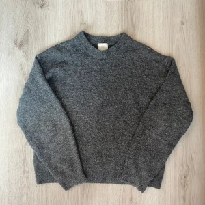Grå stickad tröja från H&M - Mysig grå stickad tröja från H&M i storlek XS. Tröjan har en klassisk rund halsringning och långa ärmar. Den är lite nopprig. 