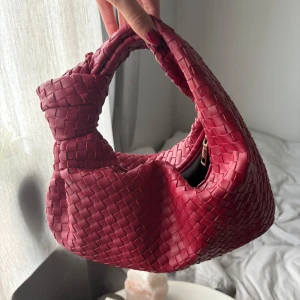 Röd flätad väska i skinn - Säljer en snygg röd axelväska med flätad design och chunky handtag!