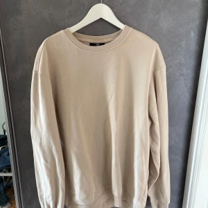 Beige sweatshirt från H&M - Enkel och stilren beige sweatshirt från H&M med rund halsringning och långa ärmar. Tröjan har en relaxed fit och är tillverkad i mjuk bomull, perfekt för en chill och avslappnad look. Passar till allt och är superenkel att matcha.