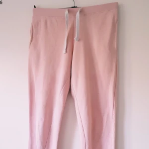 Ljusrosa mjukisbyxor med snörning - Mysiga ljusrosa mjukisbyxor med vit snörning i midjan. Byxorna har en relaxed passform och är tillverkade i mjukt material som känns skönt mot huden. Perfekta för chill dagar hemma eller när du vill vara extra bekväm.  Helt skick dock noppriga