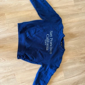 Blå sweatshirt från Zara med tryck - Blå sweatshirt från Zara i storlek S med vitt tryck på bröstet där det står 'San Francisco California'. Tröjan har rund hals, långa ärmar och ribbade muddar. Perfekt för en chill och avslappnad stil.
