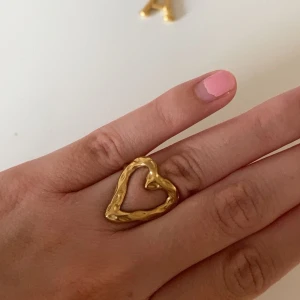 Guldig hjärtformad ring - Trendig ring i guldton med öppen, handgjord känsla och hjärtformad design. Den har en organisk, lite ojämn yta som ger en cool och unik look. Perfekt statement-piece för dig som gillar smycken som sticker ut.