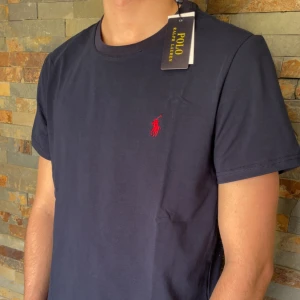 Polo Ralph lauren T-shirt  - En riktigt snygg mörkblå Ralph lauren T-shirt. Denna T-shirt är väldigt välkänd och många som vill ha den. Skicket på denna är helt ny, alltså 10/10. Storleken är M. Priset jag kommer sälja denna T-shirten för är 399kr men kan sänka vid snabb affär så kom med förslag. Sedan så kontakta mig om ni har några frågor eller funderingar. Mvh