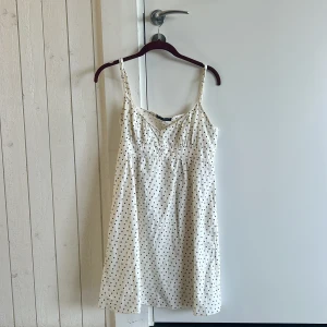 Vit blommig kortklänning Brandy Melville - Supersöt vit kortklänning från Brandy Melville med tunna axelband och små blå blommor över hela tyget. knappar framtill avslappnad och klassisk brandy look. One size/Xs/S. 