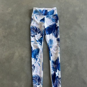 Stronger Blommiga leggings - Snygga leggings med tropiskt blommönster i blått och vitt, samt små rosa blommor. Hög midja och tight passform, perfekta för träning eller chill. Materialet är mjukt och stretchigt syntet. Fräscha  och riktigt sköna