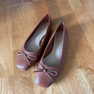 Bruna ballerinaskor från Sergio Bardi - Snygga bruna ballerinaskor från Sergio Bardi i skinn med fyrkantig tå och söt rosettdetalj framtill. Skorna har platt sula och klassisk design som passar perfekt till jeans eller klänning. Enkla att matcha och superbekväma för hela dagen.