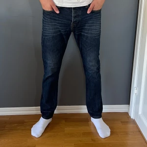 Mörkblå jeans från Farrell  - Snygga mörkblå jeans från Farrell med klassisk femficksdesign och diskreta slitningar framtill. Jeansen har raka ben och normal passform, tillverkade i slitstarkt bomullstyg. Perfekta för dig som gillar en enkel och stilren look. Storlek W34 L30