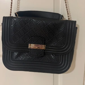 Svart quiltad axelväska från Guess - Snygg svart axelväska från Guess med quiltat mönster och guldfärgad kedja 🌸❤️