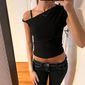Svart one shoulder croppad topp - Snygg svart croppad topp med one shoulder och korta ärmar. Tröjan har inte använts och är precis som ny! Pris kan diskuteras🌺