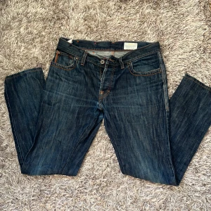 Blå Boss jeans regular fit W33/L34 - Snygga blå jeans från Boss med regular fit och klassisk femficksdesign. Jeansen har orange kontrastsömmar, läderpatch med Boss-logga bak och raka ben. Tillverkade i slitstarkt denim för en tidlös look.