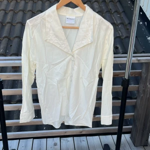 Vit skjorta med broderad krage H&M - Vit långärmad skjorta från H&M Woman Collection i storlek 36. Skjortan har en snygg broderad krage, knappar framtill och är tillverkad i ett lätt och mjukt tyg. Perfekt för dig som gillar en clean och klassisk look med en twist.