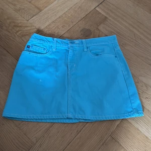 Blå jeanskjol från Ralph Lauren - Supersnygg blå kort jeanskjol från Ralph Lauren Polo Jeans Company. Klassisk femficksmodell med bälteshällor och tydliga sömmar. Perfekt för dig som vill sticka ut med en färgglad look. Märkespatch bak i midjan och logga på bakfickan. Mycket bra kvalitet, från ca. 2001. Strl 34-36