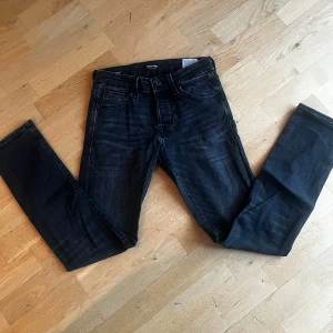 Svarta jeans från Jack & Jones stl 27/30 - Snygga svarta skinny jeans från Jack & Jones med klassisk femficksdesign och diskreta slitningar. Jeansen har smal passform och är tillverkade i stretchig bomullsblandning för extra komfort. Perfekta för dig som gillar en stilren och modern look. Hör av er vid frågor och funderingar🙌