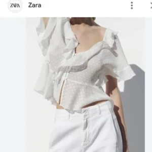 Vit blus med volanger från Zara - Säljer en söt vit blus från Zara med volanger och knytning framtill. Blusen har ett prickigt mönster och korta ärmar. Perfekt för en somrig look! Använd väldigt få gånger 💓Storlek m men skulle säga den är liten i storlek💖pris kan diskuteras vid snabb affär💓Sista bilden är lånad