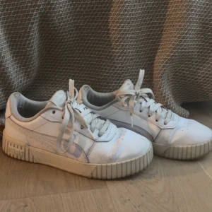Vita sneakers från Puma - Säljer ett par vita sneakers från Puma med snörning och en robust sula. Skorna har en klassisk design med Pumas logga på hälen och sidan. Perfekta för en avslappnad stil.