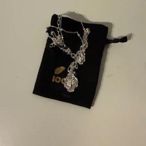 IOAKU Silverfärgat halsband med skorpionmedaljong - Elegant silverfärgat halsband med en detaljerad medaljong av en skorpion. Kedjan är fin och smidig, perfekt för att ge en stilfull touch till din outfit. Medaljongen har ett intrikat mönster som ger en vintagekänsla. Lång kedja HELT NY