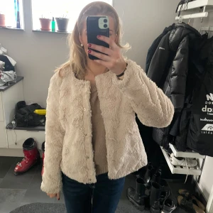 Beige teddyjacka - Säljer en mysig beige teddyjacka med långärmad design. Jackan har en normal passform och stängs med knappar framtill. Perfekt för kyligare dagar när du vill hålla dig varm och stilren.