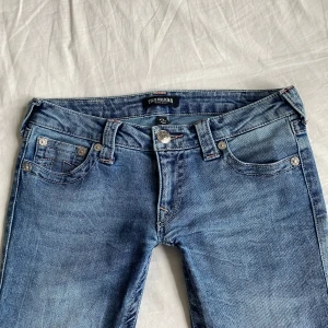 Blå bootcut jeans från True Religion💓 - Snygga blå bootcut jeans från True Religion med rosa detaljer💗De är använda 1 gång så i jättefint skick💕Skriv för för fler frågor och privata bilder💕