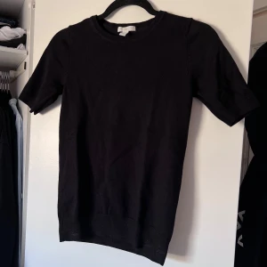 Svart finstickad tröja - Säljer en stilren svart kortärmad tröja från H&M Basics. Perfekt för en enkel och klassisk look. Tröjan har en rund halsringning och är tillverkad i ett mjukt finstickat material som ger en bekväm passform. Önskar du veta exakta mått? Tveka inte att höra av dig!