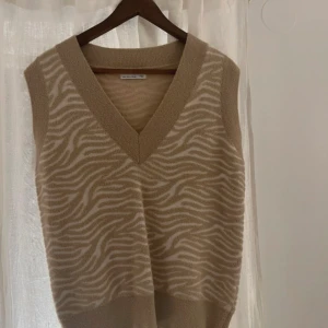 Beige vit zebramönstrad väst från Zara - Snygg beige och vit väst från Zara med zebramönster. Den har en v-ringad design och är perfekt för att lägga till lite stil till din outfit. Västen är i en mjuk och bekväm kvalitet.